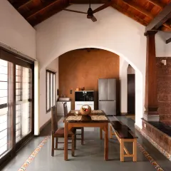 A view of the dining hall in our Vinaya residence project. This space is defined by an arch leading to the kitchen, a high vaulted wooden ceiling, and a Lohi lime plaster accent wall, demonstrating how natural materials create warm and functional living areas.