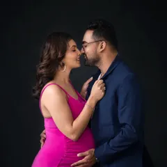 An intimate and classic studio portrait against a dark backdrop. The vibrant pink dress adds a pop of color, while the pose highlights the couple's close connection.