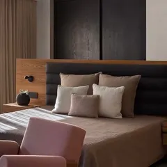 Sunlight streams into this bedroom at the Mango Orchard House, highlighting the natural textures of the bedding and the warm tones of the custom wood headboard.