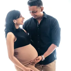A high-key studio portrait with a pure white background creates a light, airy, and modern feel. This image beautifully highlights the couple's joy and the elegant shape of the baby bump.