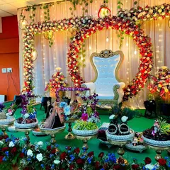 A beautiful baby shower or engagement stage featuring a circular floral arch with hanging lights. The entire setup is brought to life with dozens of my decorated trays, each filled with fruits, sweets, and gifts, all arranged on a green-covered stage.