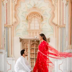 Against the magnificent arches of Jaipur's Patrika Gate, he asked for her forever. The vibrant red of her saree and the grandeur of the setting create a truly royal proposal photograph.