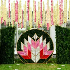 A straight-on view of the geometric floral lotus backdrop for the naming ceremony. The vibrant pink, red, and white petals create a striking and artistic centerpiece for the event.