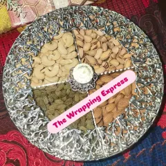 A classic dry fruit platter presented in an elegant silver-finish dish, with separate sections for cashews, pistachios, almonds, and raisins.