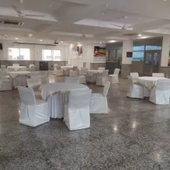 A classic banquet hall setup for a formal gathering. We arrange round tables with clean white linens and chair covers, ensuring a neat and organized space ready for guests.