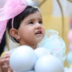 A sweet portrait of the birthday girl looking up, with a large pink bow in her hair. Close-up shots like this highlight the adorable details and expressions of your little one.