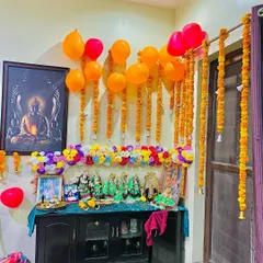 This is the same pooja corner setup, showing how the combination of traditional genda flowers and bright balloons can make a space feel ready for any happy occasion.