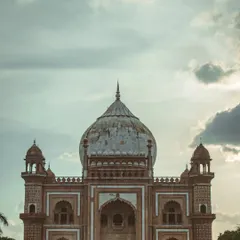 A dramatic shot of Safdarjung Tomb against a cloudy sky. The architecture is the hero here, and the moody sky adds a sense of history and grandeur to the monument.