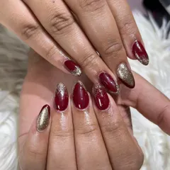 Another angle of these stunning bridal nails, showcasing the combination of rich red gel polish and gold glitter on almond-shaped extensions.