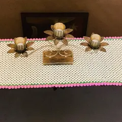 This simple yet beautiful table runner features a cream-colored granny stitch pattern with a bright pink tulip border. It's shown here on a console table with a candle stand.