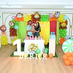 Welcome to the jungle! For Derick's first birthday, I transformed the space into a vibrant safari adventure. This full-stage setup includes a colorful balloon arch with animal foils, character cutouts, a lighted number '1', and personalized marquee letters, showing how I handle end-to-end themed party planning.
