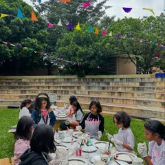 An outdoor birthday party in full swing. Here, a group of friends are completely absorbed in making their own moon lamps, surrounded by nature and festive decorations.