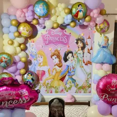 A magical Disney Princess party. This decoration uses a pastel balloon garland to frame a large backdrop featuring Cinderella, Belle, Ariel, and other princesses, creating a fairytale setting.