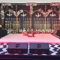 A stage ready for a night of performances. This setup includes a dance floor, professional speakers, and a beautifully decorated backdrop with floral arches and chandeliers.
