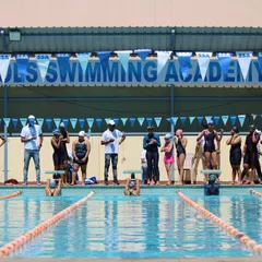 Swimmers on the starting blocks, focused and ready for the whistle at the Sasthapools Swimming Academy competition.