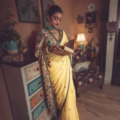 Creating a story through styling. In this shot, the model, dressed in the elegant yellow saree and embroidered blouse, interacts with the vintage-inspired set, adding a narrative quality to the fashion photograph.