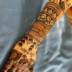 A beautiful full-hand design that showcases a variety of classic elements. It includes hanging 'jhumkas', an elephant, the couple's names, and a peacock at the top, all woven together with floral and architectural bands.