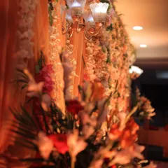 A detail shot from an indoor engagement setup, focusing on a vintage-style lamp fixture attached to the dense floral wall. This shows how we integrate lighting elements directly into our decor for a seamless, warm glow.