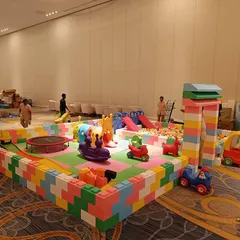 Another angle of our large play area, highlighting the different components like the mini trampoline, train rider, and various small cars. The modular design allows us to fit different venue sizes and shapes.