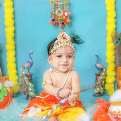 A happy little Kanha with his peacock feather. The bright blue backdrop adds a vibrant and playful touch to this divine theme.