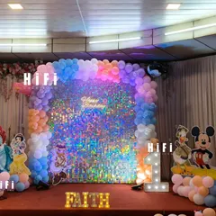 This Disney-themed first birthday stage features a sparkling sequin wall and character cutouts of princesses and Mickey Mouse. The design is framed with pastel balloons and personalized with the number '1' and the name 'FAITH' in marquee lights.