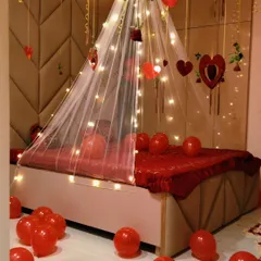 A close-up of the romantic bed canopy, decorated with fairy lights and hanging heart ornaments. The all-red theme is perfect for creating a passionate and loving atmosphere.
