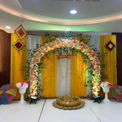 A perfect Haldi setup. This one has a beautiful floral arch in pastel colors against a bright yellow backdrop, with traditional Rajasthani umbrellas and a lotus-shaped seating area for the ceremony.
