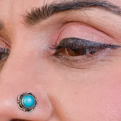 A close-up of a beautiful oxidized silver nose stud with a turquoise stone. This is a perfect example of a traditional design that is always in style.