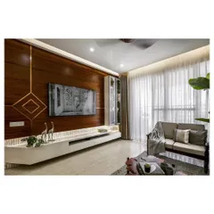 The living room features a full-height wooden entertainment wall with a sleek, floating console. The warm wood tones are balanced by the light-colored flooring and sheer curtains, making the space feel expansive and bright.