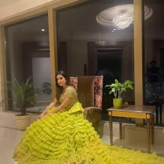 A close-up of our multilayered yellow ruffled gown with a mirror-embedded peplum top. This is a trending pick for a mehendi, combining traditional elements with a high-fashion silhouette.