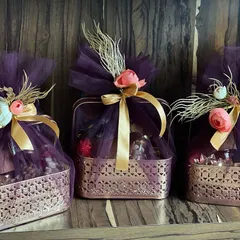 A set of three elegant Diwali hampers. The rich purple netting, gold ribbons, and delicate floral accents create a luxurious and festive look, perfect for the festival of lights.