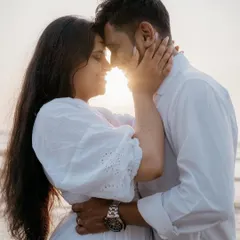 An intimate close-up of a couple embracing on the beach, their faces lit by the setting sun. This photo focuses on their deep connection, making it a perfect example of romantic couple photography.
