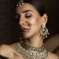 A detailed beauty shot focusing on the bride's exquisite jewellery and makeup. This close-up highlights the intricate nath, choker, and earrings, essential for bridal jewellery campaign photography.