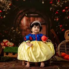 Once upon a time in my studio. This little girl is dressed as Snow White, holding an apple in an enchanted forest setting, bringing a classic fairytale to life.