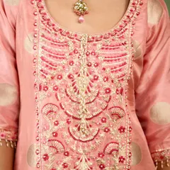 A close-up of the exquisite hand-embroidery on the pink sharara kurta. The combination of zardozi and threadwork in shades of pink and gold highlights the artisanal finesse of the piece.