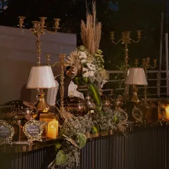 A close-up of our elaborate buffet decor. We use a mix of elements like tall candelabras, modern lamps, and lush floral arrangements with dried pampas grass to create a rich, textured, and luxurious look.