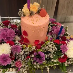 Gifting in style. This birthday cake platter features a beautiful mix of roses and chrysanthemums, creating a lush floral base for the main dessert.