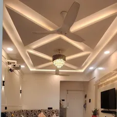 A completed project showing a geometric false ceiling design with integrated cove lighting and a central chandelier. This is how I use POP work to add drama and elegance to a living room.