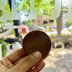 Holding up one of our millet jaggery cookies to the light. It's a simple, honest cookie that I'm very proud of. The deep color comes from the combination of millet and jaggery.