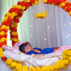 A traditional Marathi naming ceremony, or 'barsa'. This shot captures the baby peacefully resting in a beautifully decorated floral cradle, a key moment of the ceremony.
