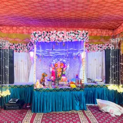 A complete Ganpati pandal decoration. This setup includes a decorated stage with a floral and light-up arch, a sequined backdrop, and proper seating for the idol.