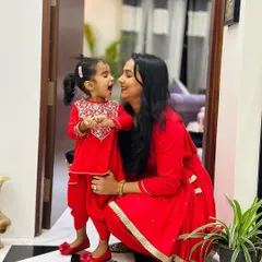 A candid moment of joy between a mother and her mini-me. They are both wearing our custom-designed tomato red peplum kurta and tulip pants sets, a vibrant and playful choice for any celebration. The daughter's outfit features delicate embroidery on the yoke.