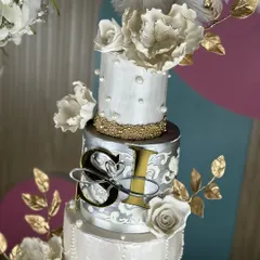 A masterpiece for a love that shines. This silver and pearl-themed wedding cake, framed by a floral hoop, combines intricate textures, delicate sugar flowers, and shimmering details for a look of timeless elegance.