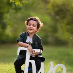 Celebrating the big TWO. This outdoor milestone portrait captures the pride and joy of a two-year-old, with beautiful natural light and a simple prop to mark the occasion.