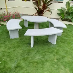 This is a complete garden dining set I made, with four curved stone benches and a round stone table, installed on a lawn.