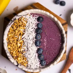 A top-down view of a beautifully arranged blueberry smoothie bowl. This kind of shot is very popular on social media and is perfect for a healthy cafe's menu.