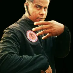 A portrait capturing the focus and readiness of a martial artist. The hand is ready to block or strike, and the eyes are watchful.