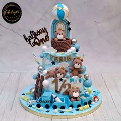 We created this detailed two-tier chocolate cake to celebrate a "Halfway to One" milestone. It's packed with a teddy bear theme, including a hot air balloon, a fondant train, and playful teddies.