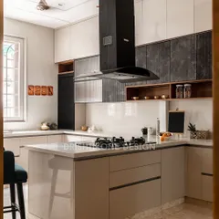 This U-shaped kitchen is designed for ultimate efficiency and style. It features handle-less cabinets, a mix of glossy beige and matte black fluted shutters, and an integrated breakfast counter for casual meals.