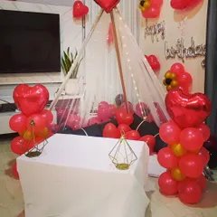 A cozy floor seating arrangement for an intimate birthday celebration. I created a teepee-style canopy with fairy lights, surrounded by red heart-shaped foil balloons and balloon bunches.